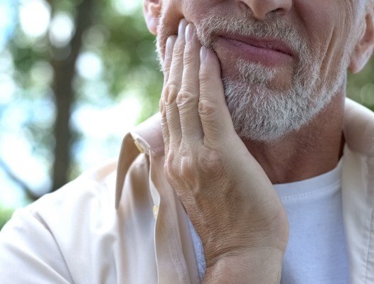 Man with extruded tooth holding jaw in pain