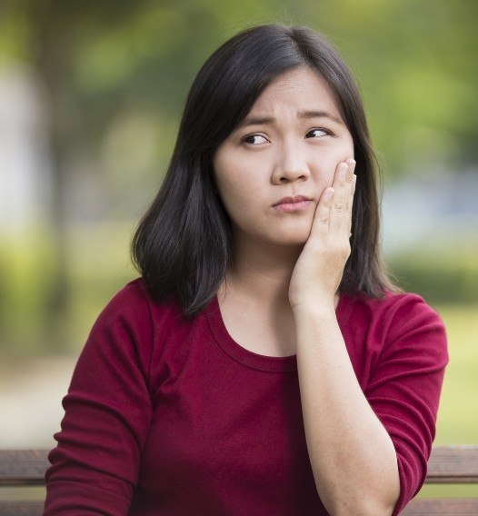 Woman in need of emergency dentistry holding jaw in pain