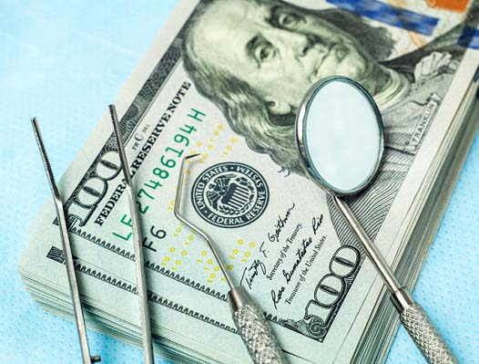 Dental tools and money representing the cost of dental emergencies in Phoenix
