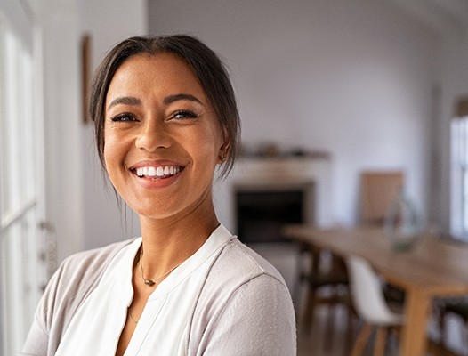 Woman sharing flawless smile after dental implant tooth replacement