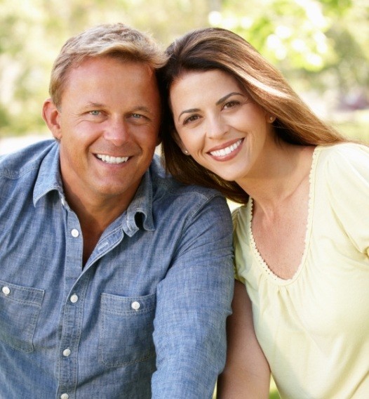 Man and woman smiling after tooth replacement with dental implants