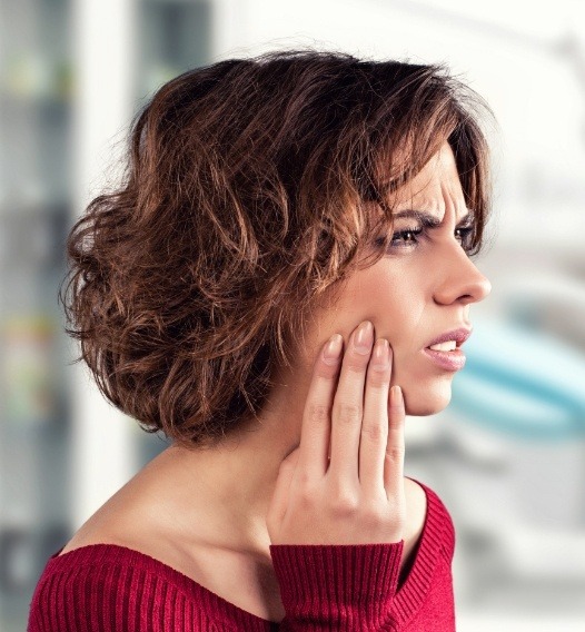 Woman in need of emergency dentistry holding cheek in pain