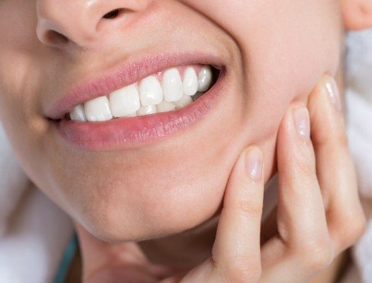 Woman in need of root canal therapy holding jaw in pain